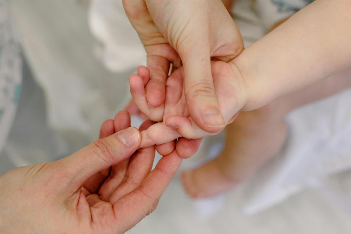 Babymassage - Mutter massiert kleine Hand